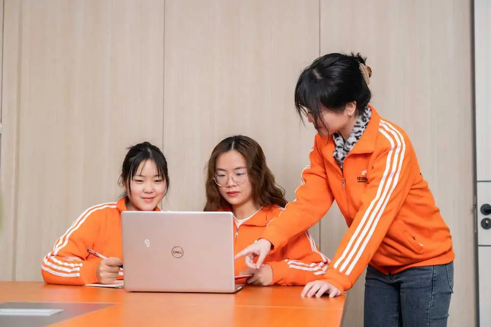 three people in front of a laptop discussing