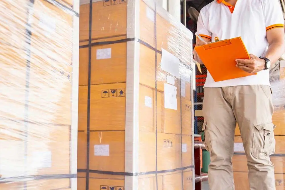 man holding orange clipboard checking cargo